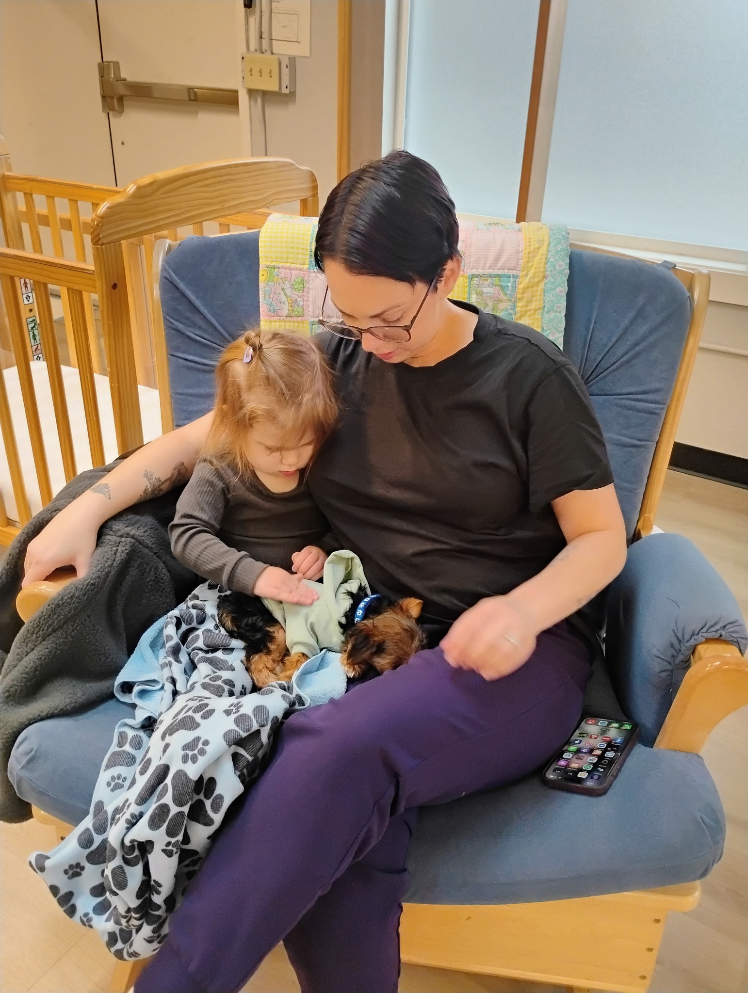 An educator and child gently spending time with a visiting puppy in the classroom